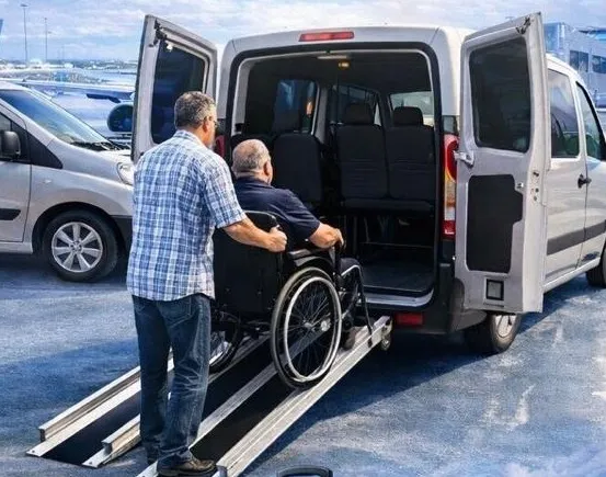 Chofer ayudando a un pasajero en silla de ruedas a subir por la rampa de la van